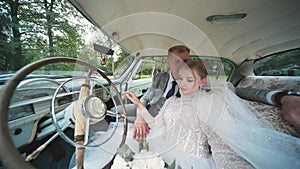 Bride and groom enjoying each other in a retro car.