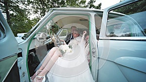 Bride and groom enjoying each other in a retro car.