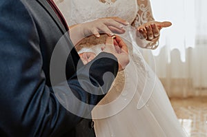 The bride and groom exchange rings. A man puts a wedding ring on a woman& x27;s hand.