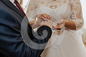 The bride and groom exchange rings. A man puts a wedding ring on a woman& x27;s hand.