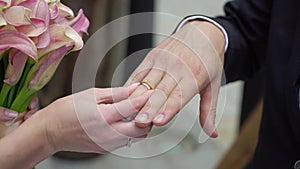 Bride and groom exchange wedding rings at ceremony. Lovely couple