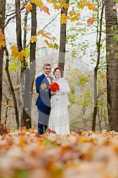 The bride and groom and falling autumn leaves