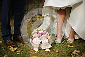 Nohy nevěsty a ženicha se svatební kyticí a svatebním perníkem