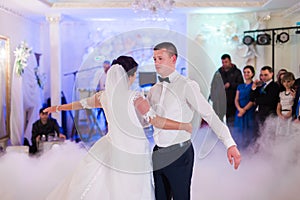 Bride and groom first wedding dance in white bright hall with blurred background