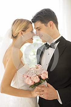 Bride And Groom With Flower Bouquet Rubbing Noses