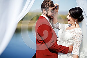 Bride and groom fooling around at photo shoot after ceremony, inside arch with white cloths fabric. Wedding Color