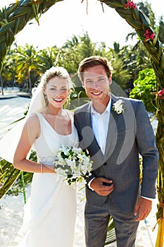 Bride And Groom Getting Married In Beach Ceremony