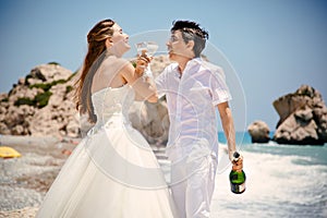 Bride and groom with glasses of champagne on the beach Mediterranean Sea