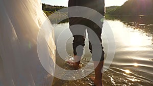 The bride and groom go barefoot on the water on the river bank. Close-up. couple in love walk on the beach hand in hand