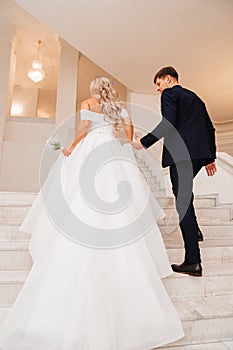 the bride and groom go up the stairs holding hands.