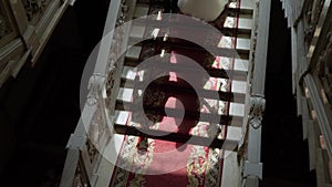Bride and groom goes down stone marble stairs in a luxurious palace or mansion.