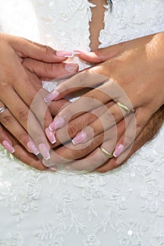 Bride and groom hands with fingers rings in wedding day on marriage dress background