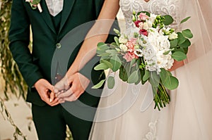 Bride and groom hands with flower bouquet