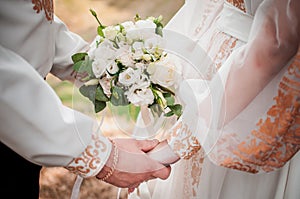 Bride and groom hands with flower bouquet