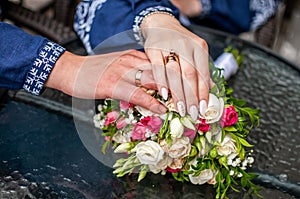 Bride and groom hands with flower bouquet on the table