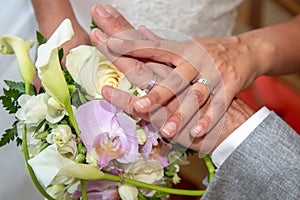 Bride groom hands of the newlyweds with wedding rings on bouquet