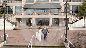 Bride and groom happily walking down stairs at wedding venue. 4K 24FPS.