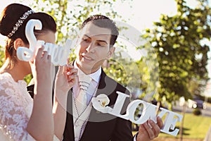 Bride and groom having fun and posing with Sweet Love letters in sunlight