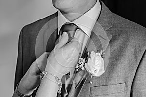 Bride groom having his tie adjusted by his mother