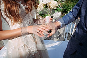 The bride and groom hold each other's hands at the wedding ring