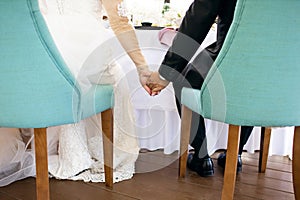 The bride and groom hold hands while sitting at a table in a restaurant