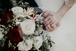 Bride and groom hold hands during a wedding ceremony in front of a wedding bouquet