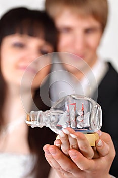 Bride and groom hold little vessel in bottle