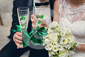 The bride and groom hold wedding glasses in hand
