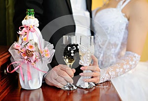 Bride and groom holding beautifully decorated wedding glasses wi