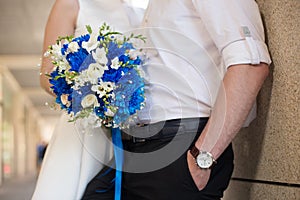 Bride and groom holding bridal bouquet of blue chrysanthemum, freesia, eustoma and peony. close up