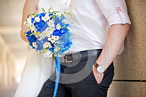 Bride and groom holding bridal bouquet of blue chrysanthemum, freesia, eustoma and peony. close up