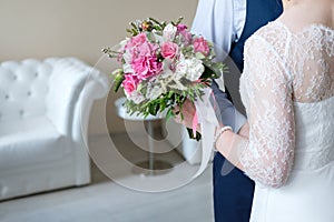 Bride and groom holding bridal bouquet close-up.