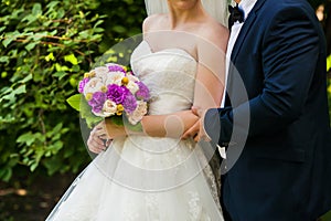 Bride and groom holding bridal bouquet close up