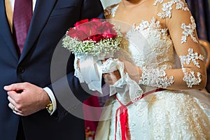 Bride and groom holding bridal bouquet close up . Red roses in brides hands