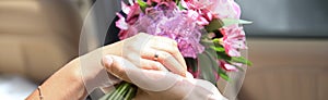 Bride and groom holding the bride`s bouquet ,sitting in the car