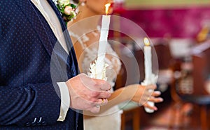 Bride and groom holding the candles. Close up