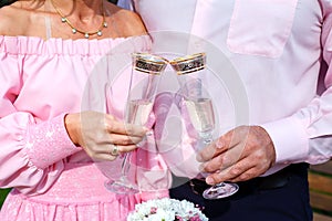 Bride and groom holding champagne glasses and bridal bouquet