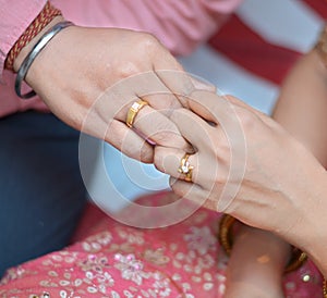Bride and groom holding fingers with engagement rings
