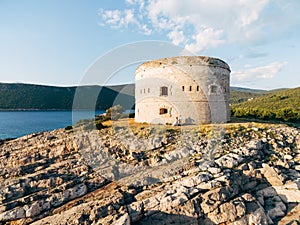 bride and groom are holding hands near the Arza fortress on the Mamula island