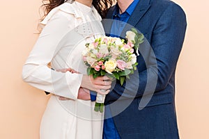 Bride and groom holding hands showing their rings, wedding couple holding bouquet