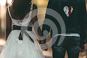 Bride and groom holding hands and walking in the park, back view photo