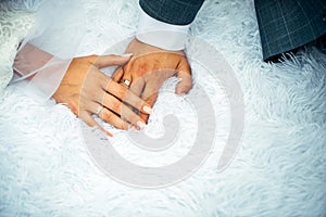 Bride and groom holding hands with woman`s hand on man`s hand with wedding rings, close up. Hands newlyweds in wedding day