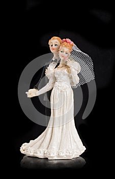 Bride and groom holding an old cake topper on a black background. Figurines for a wedding cake