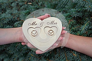 The bride and the groom are holding a ring stand in their hands - made of wood, cozy and natural, with the inscription
