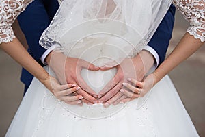 Bride and groom holding their hands in a heart shape