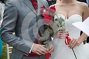 Bride with groom holding wedding red rose at ceremony