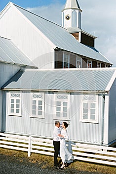 Bride and groom hug near a small church. Iceland