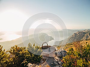 The bride and groom hug near the wedding arch on the observation deck on Mount Lovcen overlooking the Bay of Kotor