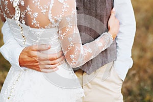 The bride and groom are hugging each other. Hands close up.