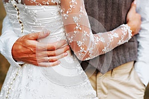 The bride and groom are hugging each other. Hands close up.